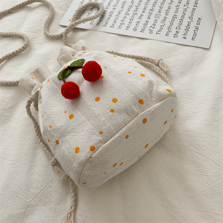 Bolsa Cherry de lona vista lateral, com detalhe das cerejas bordadas e fechamento em cordão.