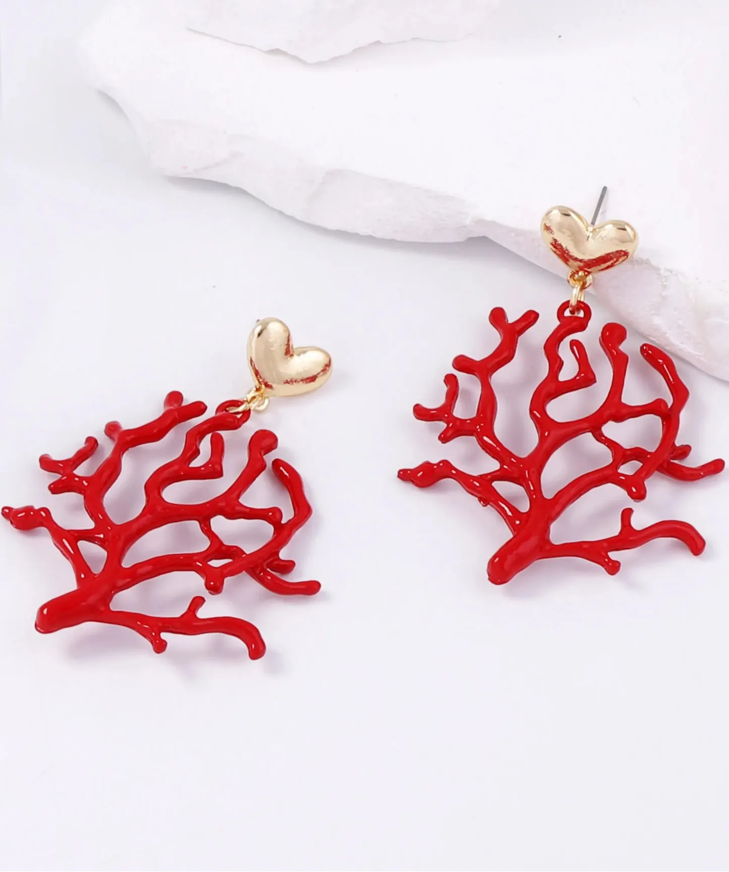 Brincos Coralina com design de coral vermelho e base dourada em formato de coração, acessório trendy e sofisticado.