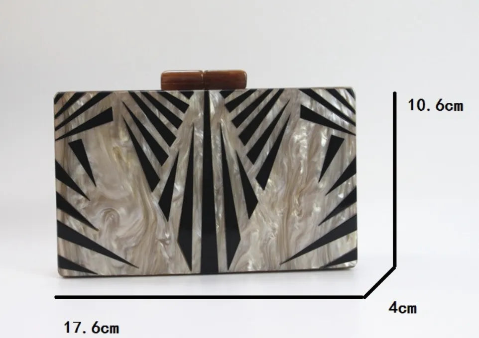 Clutch Geométrica marmorizada com design geométrico em preto, exibida com dimensões 17,6 cm largura, 10,6 cm altura e 4 cm profundidade.