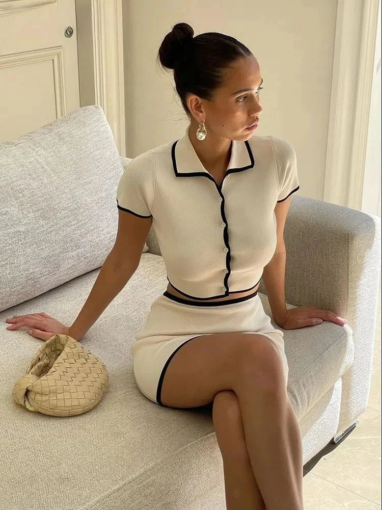Conjunto off-white com bordas pretas em estilo clássico, modelo sentada em ambiente interno sofisticado