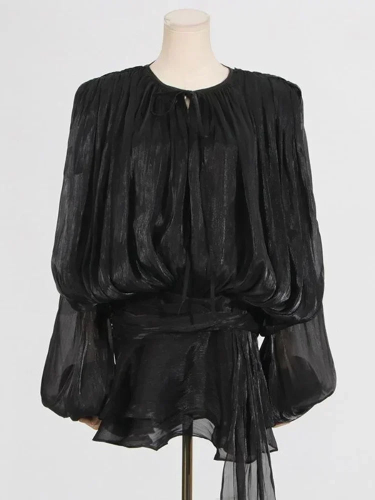 Vestido preto curto com tecido brilhante e manga bufante – opção versátil e elegante.
