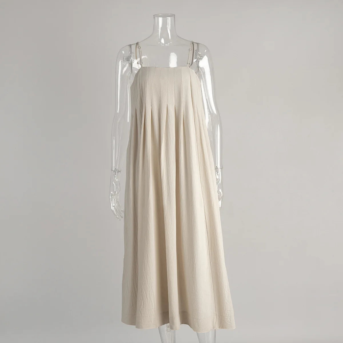 Vestido Bia em algodão bege exibido em manequim transparente, destacando a modelagem ampla e o corte reto.