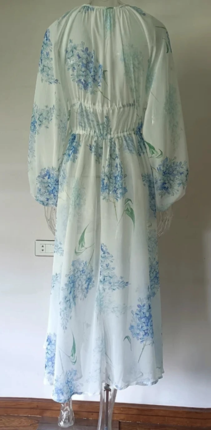 Vestido longo de chiffon floral visto por trás, com detalhe franzido na cintura e mangas amplas.