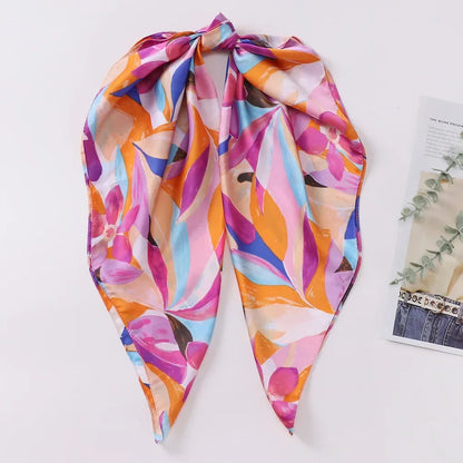 Lenco Versatile Grace com estampa abstrata em tons vibrantes de rosa, laranja e roxo, dobrado em formato triangular