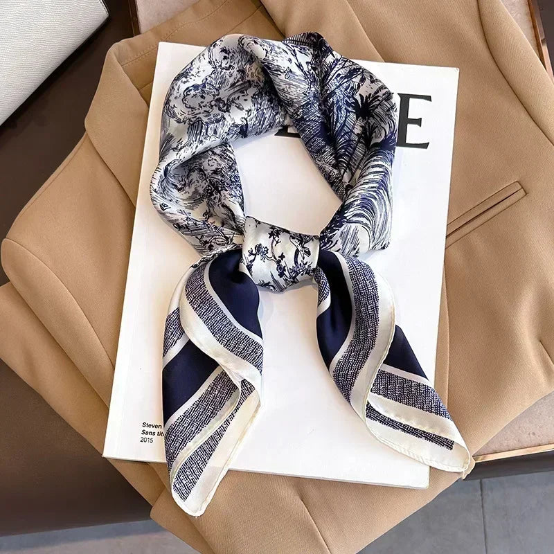 Lenco Versatile Grace amarrado no pescoço de um blazer bege, com estampa delicada azul e toque leve