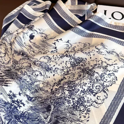 Dois lencos Versatile Grace com estampa toile de jouy azul dispostos lado a lado sobre banco marrom