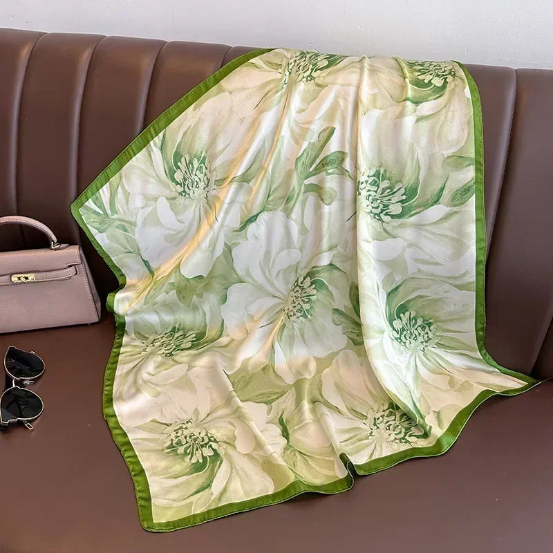 Lenco Versatile Grace acetinado com estampa de folhas tropicais em verde claro e borda verde musgo, sobre banco de couro