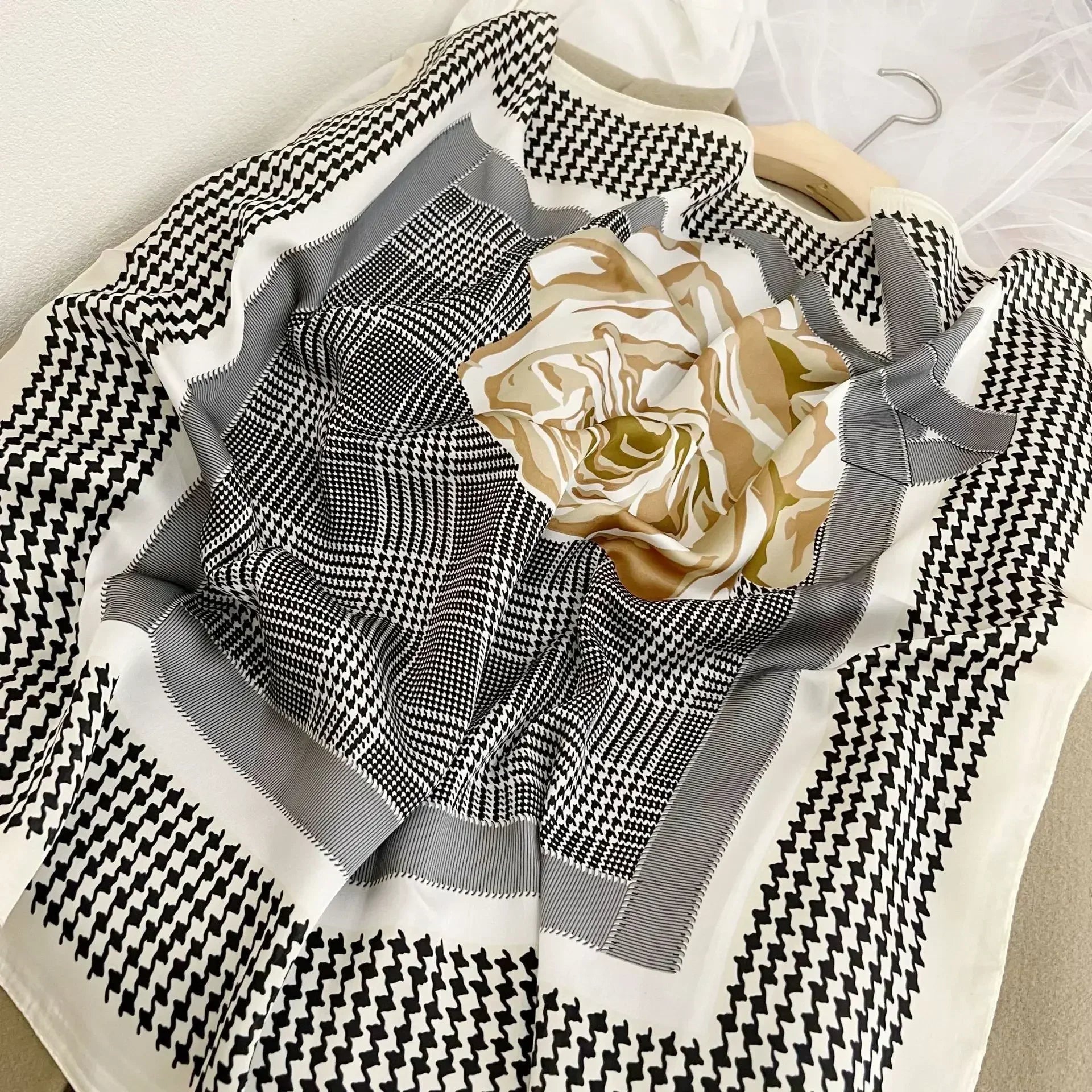 Lenco Versatile Grace com padronagem xadrez preta e branca, flor dourada central e moldura em tons de cinza claro