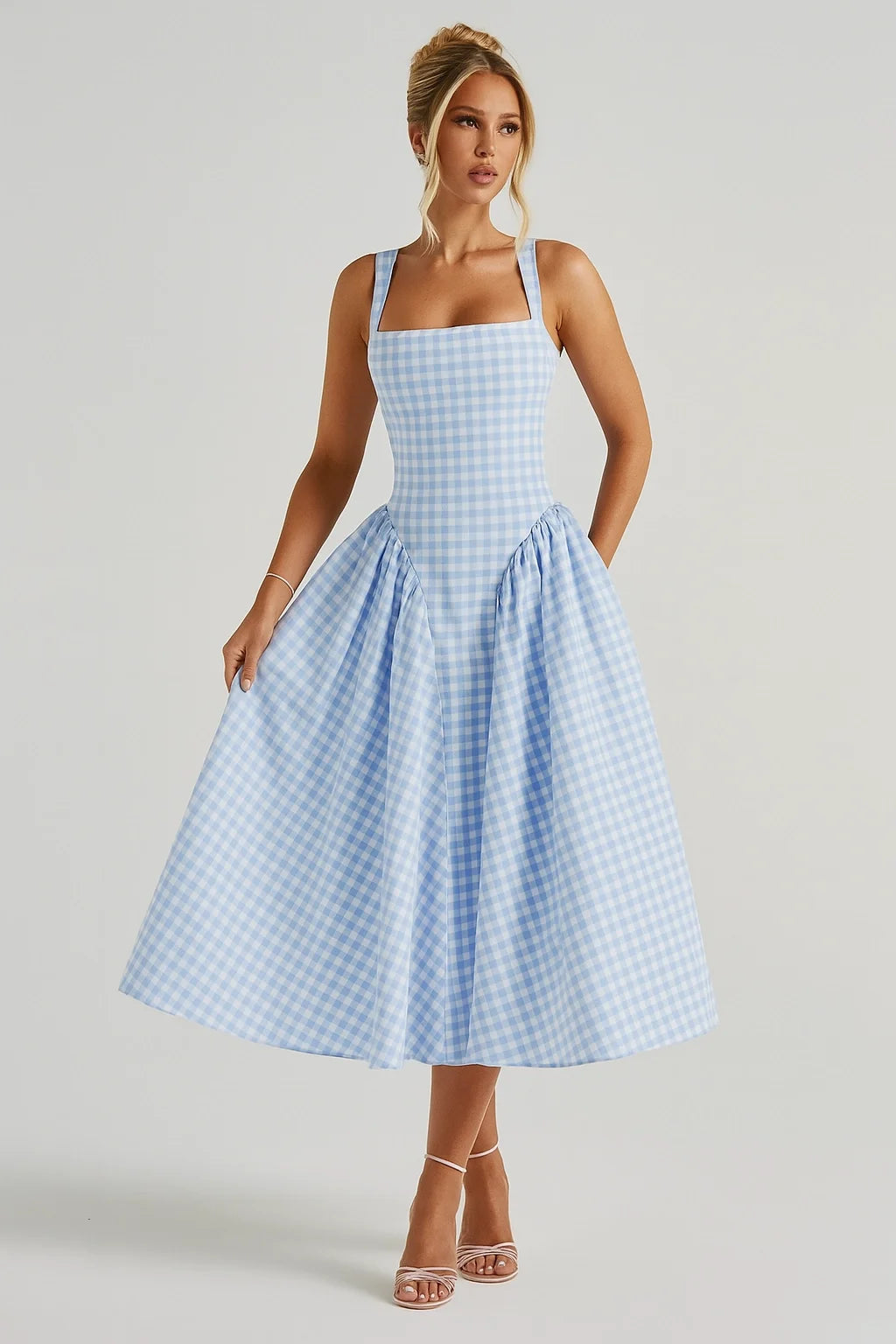 Mulher posando com vestido azul de alças largas e saia ampla, girando levemente