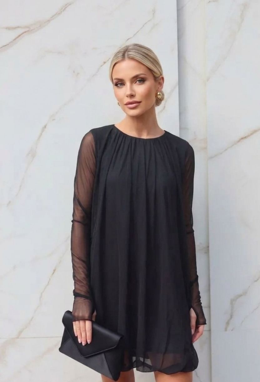 Vestido Curto Balonê DressEleven preto estilo soltinho com mangas longas em tule. Modelo posa de frente com clutch.