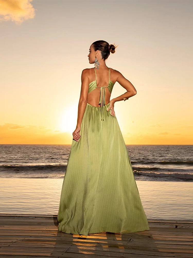 Vista traseira do Vestido Eden Verde Plissado com amarração delicada nas costas, em cenário de praia ao entardecer.
