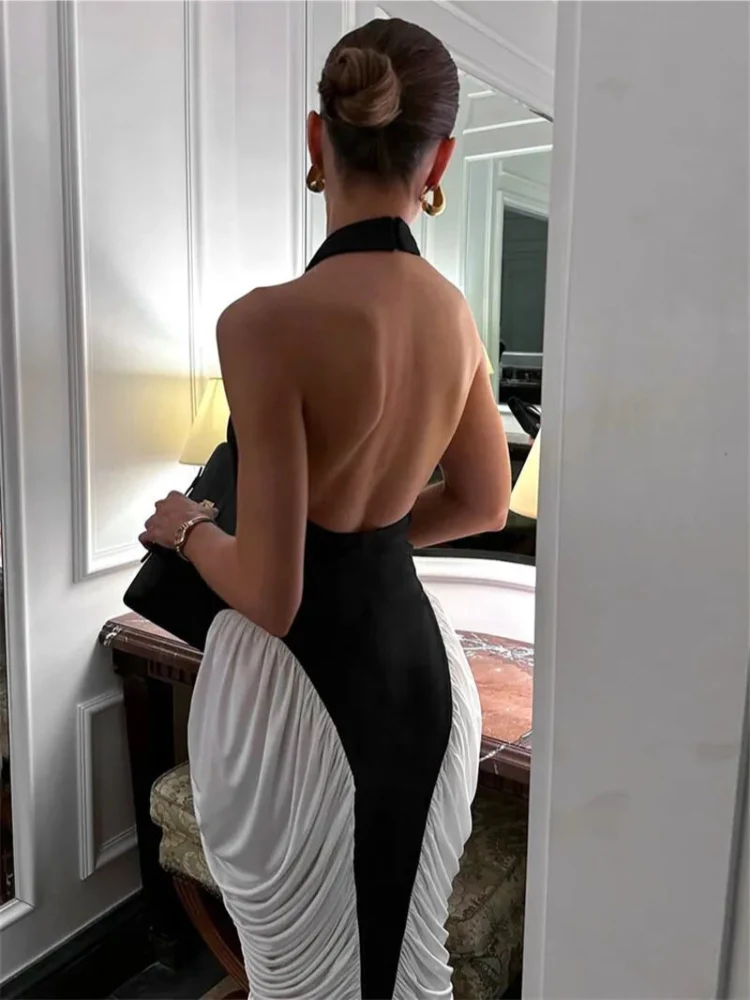 Mulher exibindo as costas abertas do Vestido Halter Bicolor preto e branco com babados laterais e cintura marcada.

