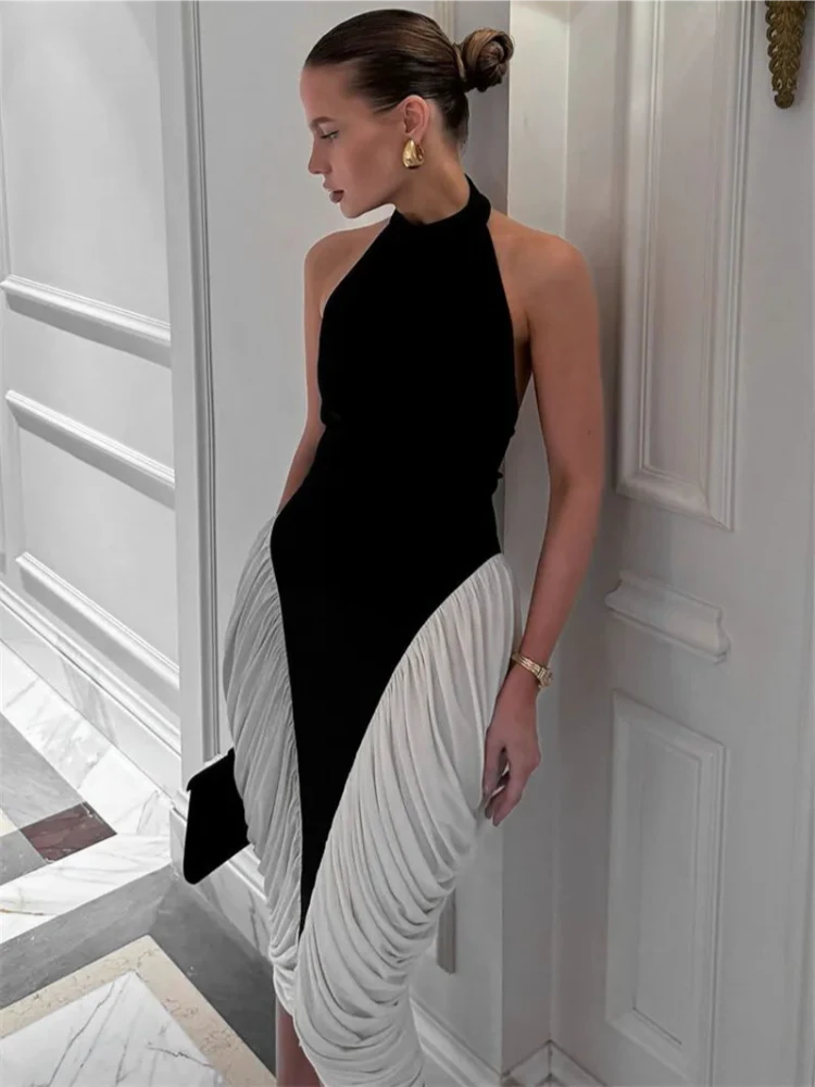 Mulher usando o Vestido Halter Bicolor preto e branco com babados laterais, posando em ambiente sofisticado.

