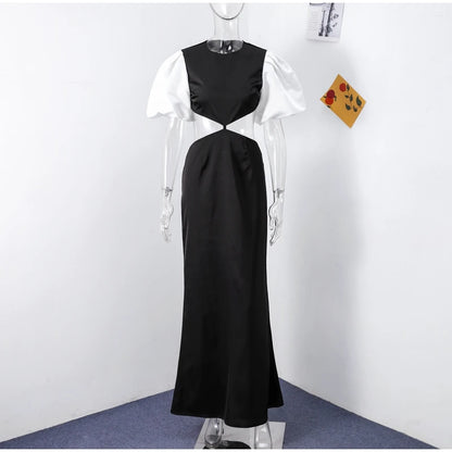 Vestido Margot preto com mangas brancas bufantes em manequim contra parede branca, mostrando caimento real