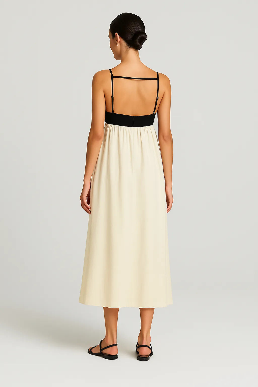 Modelo vista de costas usando o Vestido Milano, com detalhe de faixa horizontal preta e alças finas ajustáveis, destacando o design elegante e minimalista em ambiente de estúdio.