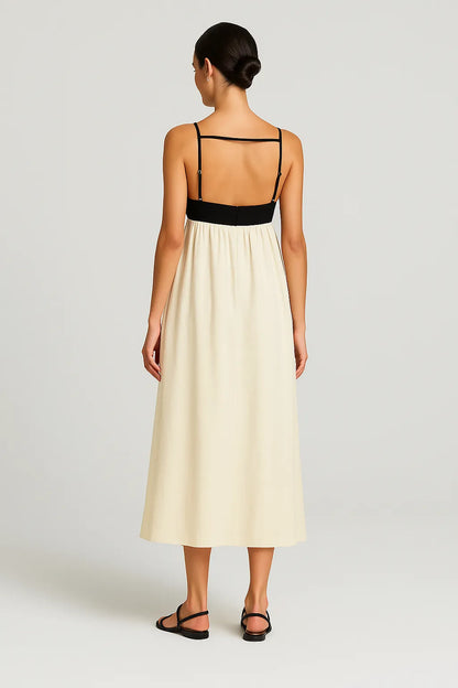 Modelo vista de costas usando o Vestido Milano, com detalhe de faixa horizontal preta e alças finas ajustáveis, destacando o design elegante e minimalista em ambiente de estúdio.