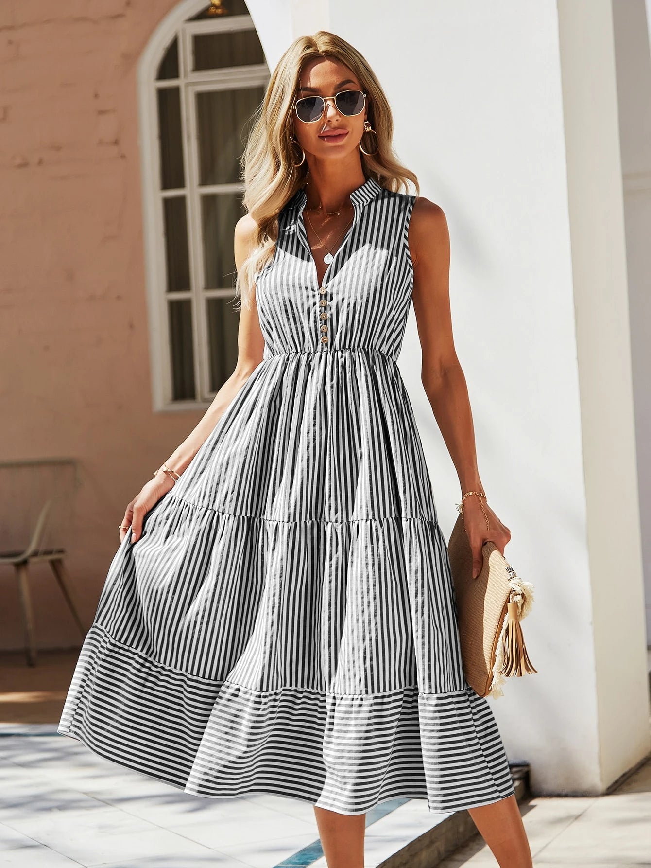 Vestido midi preto e branco com listras verticais, alças largas e saia rodada. Look sofisticado e fresco para dias ensolarados.