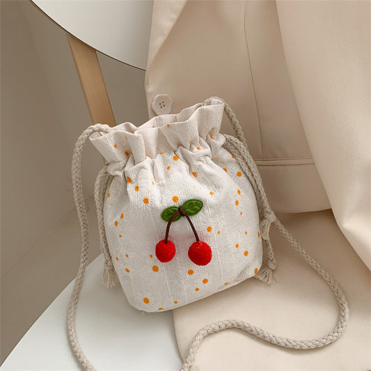 Bolsa Cherry de lona com estampa delicada e detalhe de cerejas bordadas, vista frontal sobre fundo claro.