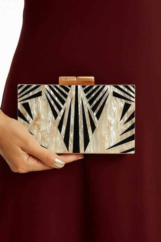 Clutch Geométrica marmorizada com estampa geométrica preta sendo usada em look sofisticado