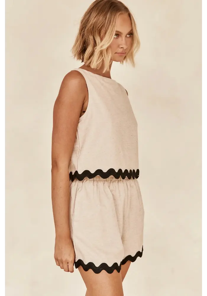 Modelo usando o Conjunto Bella visto de lado, com foco no caimento leve e detalhe ondulado preto na cintura e barra do short.