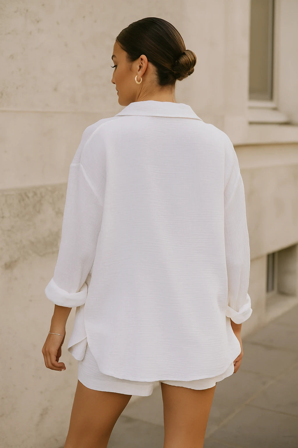 Modelo de costas usando conjunto branco minimalista com textura leve e caimento solto.