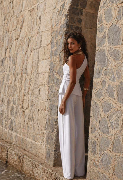 Foto externa da modelo de costas usando o Conjunto Madri branco, exibindo a modelagem da calça pantalona e a elegância do visual completo.
