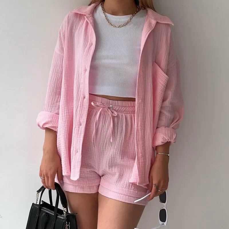 Modelo usando conjunto rosa claro com camisa e shorts texturizados, look casual com bolsa preta.