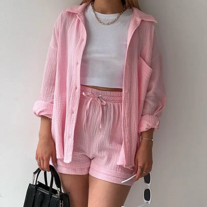 Modelo usando conjunto rosa claro com camisa e shorts texturizados, look casual com bolsa preta.