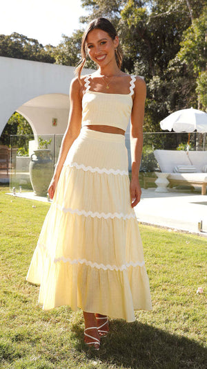 Conjunto amarelo com top cropped e saia midi rodada, ambos com acabamento ondulado branco, estilo leve e elegante para o verão