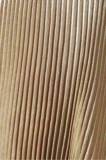 Close do tecido plissado dourado com acabamento acetinado do Vestido Vênus da Dress Eleven, evidenciando o brilho e a textura do material

