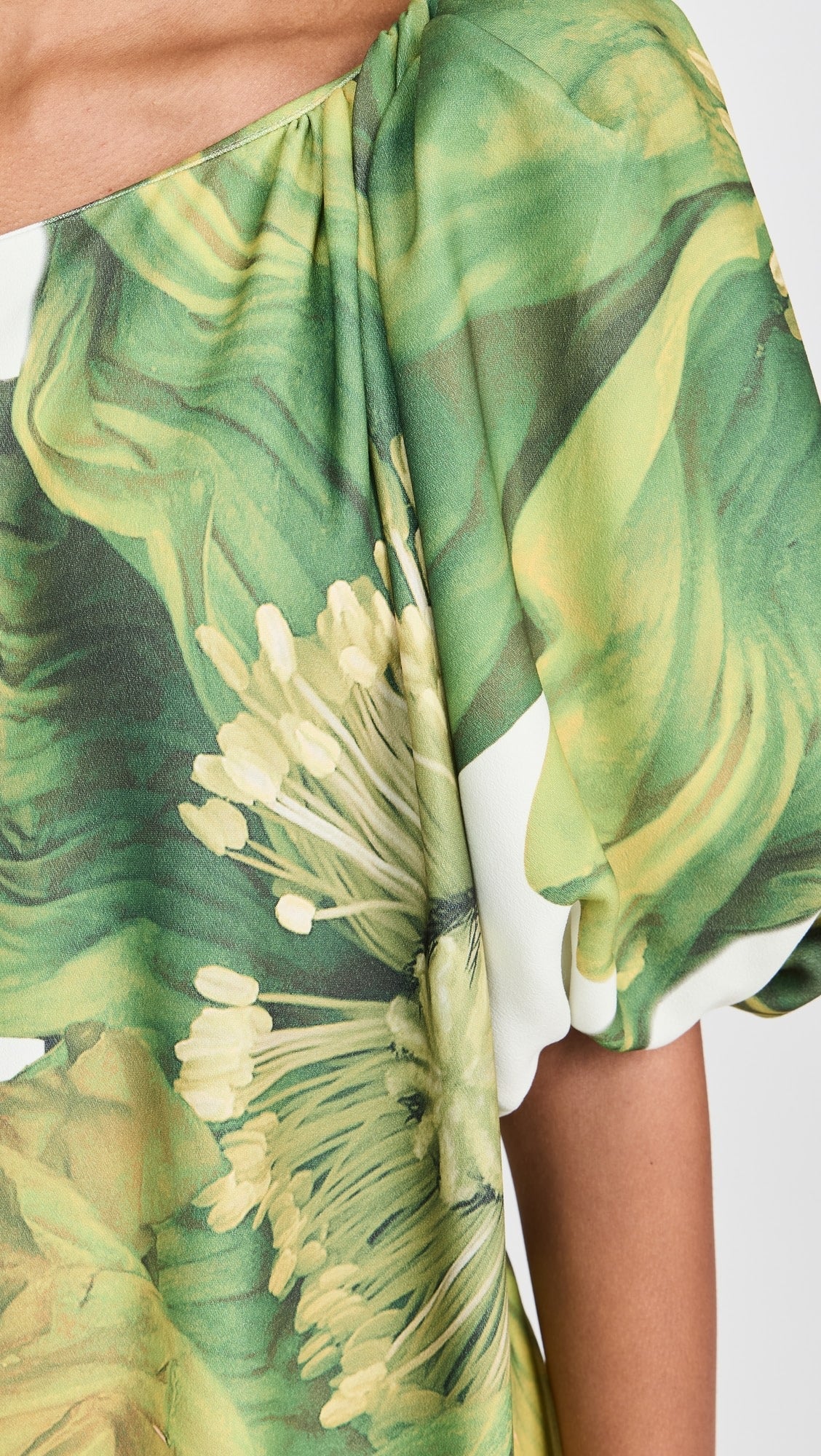 Detalhe da manga bufante do vestido Hera, com estampa floral verde sobre fundo claro e acabamento elegante.