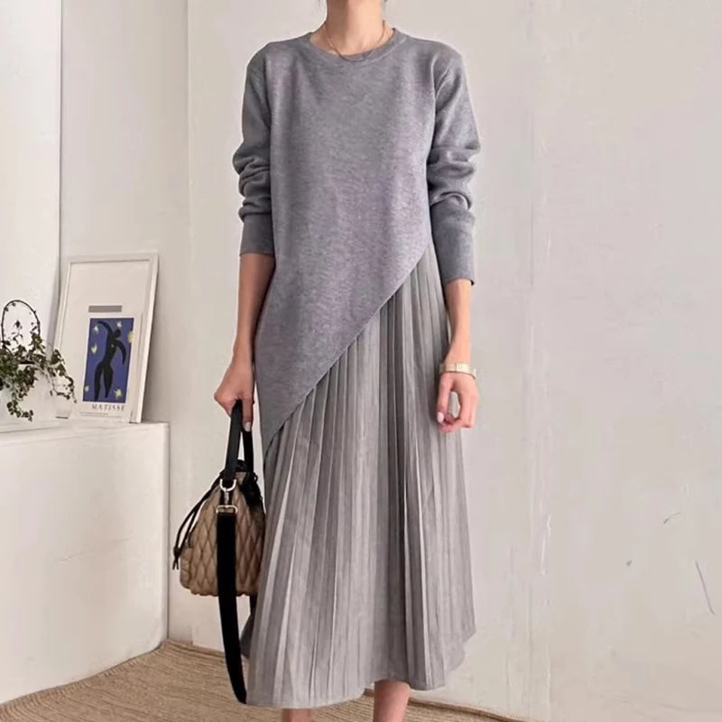 estido  cinza com design assimétrico e saia plissada, usado por modelo elegante em fundo claro. Look versátil e marcante da Dress Eleven.