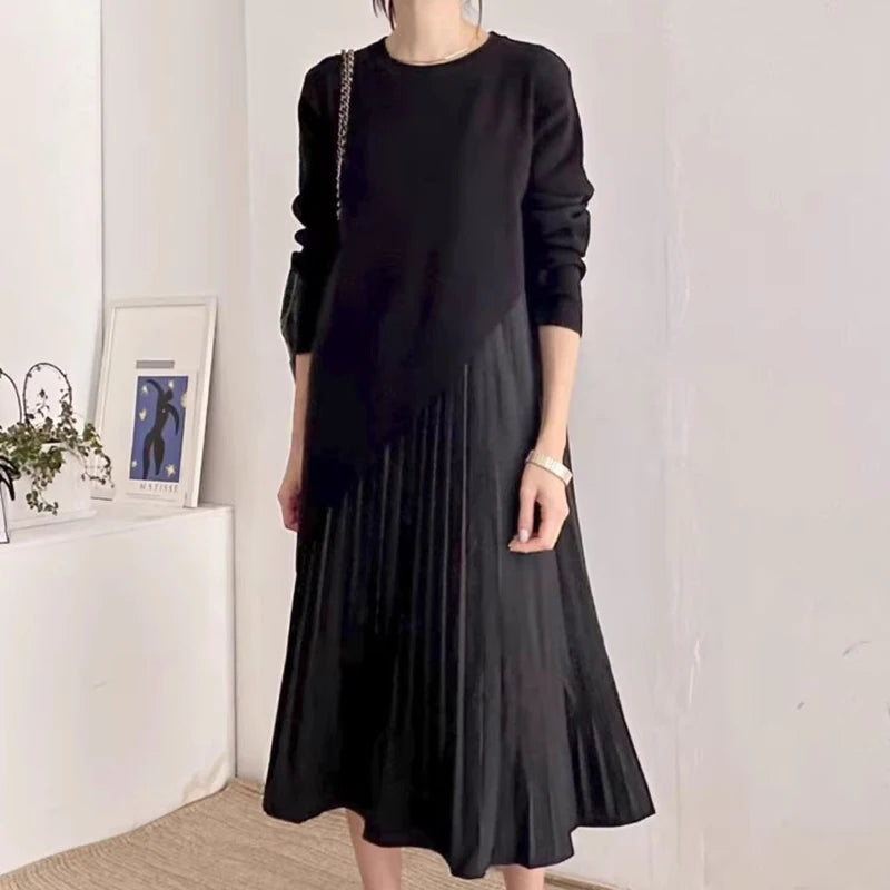 Vestido preto com design assimétrico e saia plissada, usado por modelo elegante em fundo claro. Look versátil e marcante da Dress Eleven.