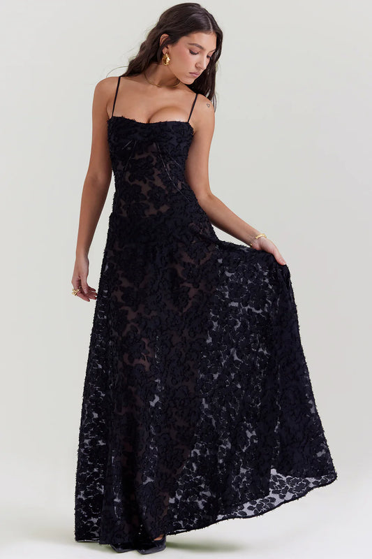 Vestido longo Blair preto em poliéster bordado, modelo segurando a saia para destacar o caimento fluido.
