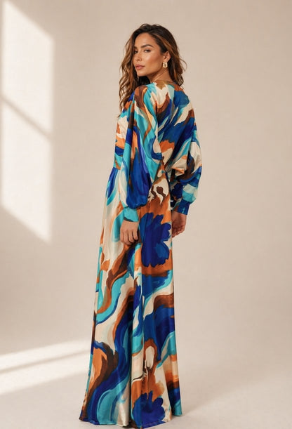 Modelo em pose ¾ usando vestido longo com mangas amplas estilo morcego, evidenciando a fluidez e elegância da peça para eventos, presente dia das mães