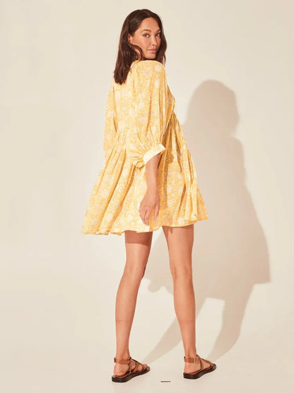 Vista lateral do vestido floral amarelo com modelagem evasê, decote em V e mangas bufantes, ideal para dias quentes.

