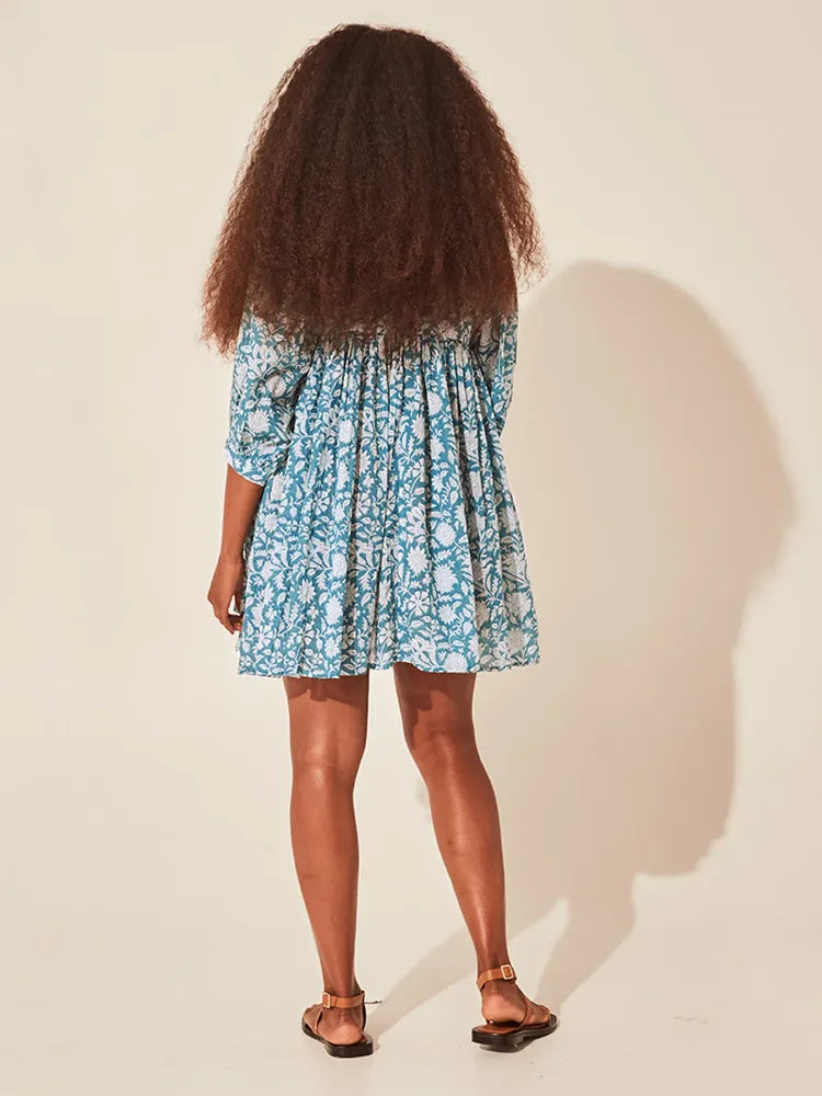Vista traseira do vestido floral azul com caimento leve e mangas bufantes, ideal para dias de verão com conforto e estilo.