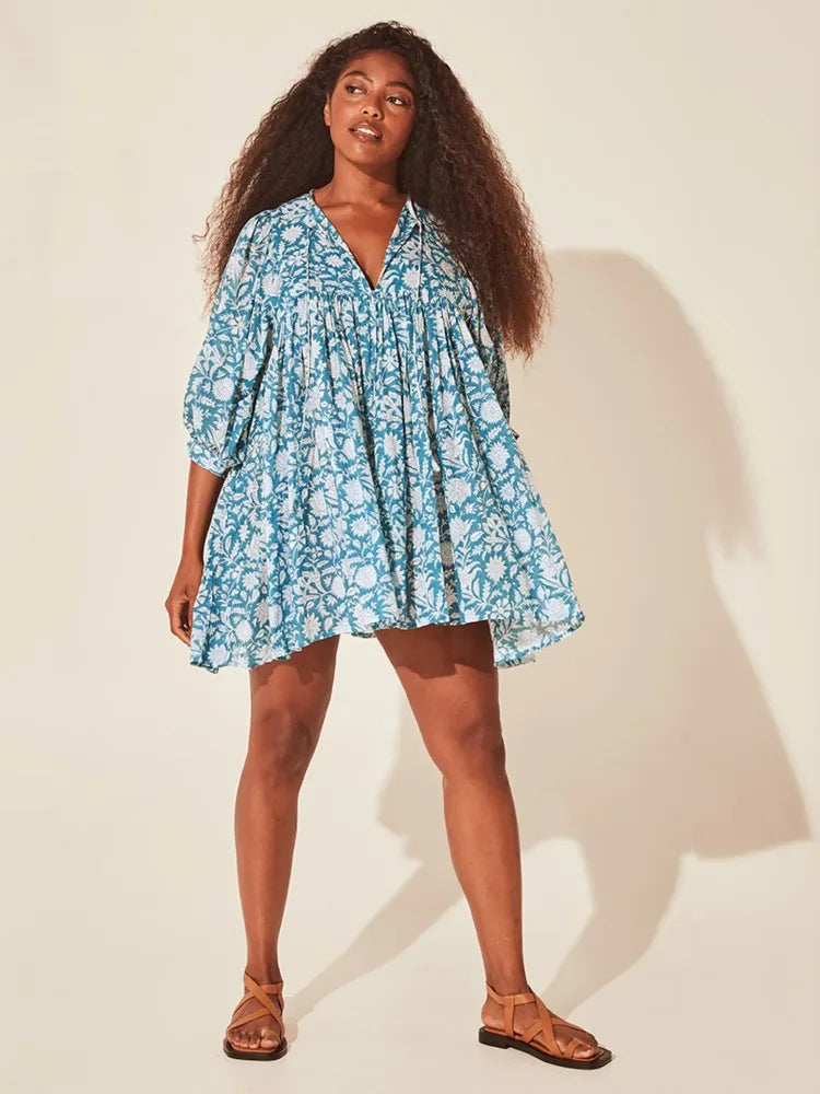 Vestido curto com estampa floral azul, mangas bufantes e modelagem ampla, fotografado de frente em estúdio com fundo neutro.