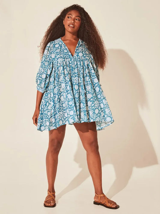 Vestido curto com estampa floral azul, mangas bufantes e modelagem ampla, fotografado de frente em estúdio com fundo neutro.