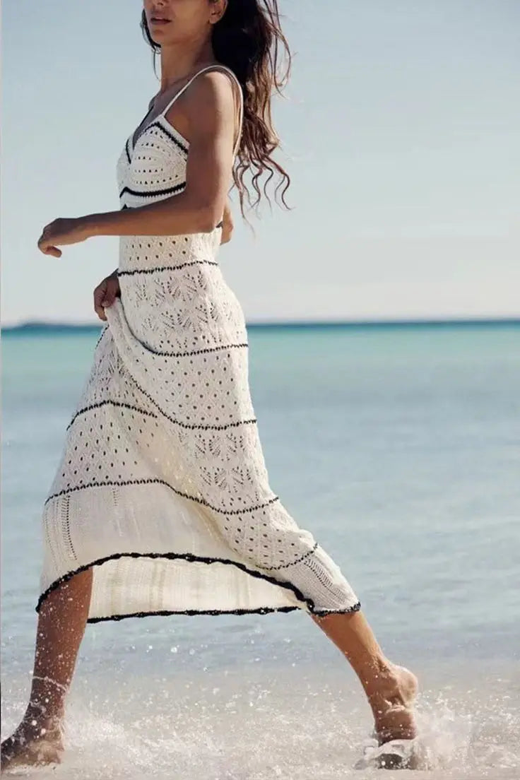 Vestido longo de crochê branco com listras pretas, em movimento à beira-mar, estilo boho-chic.