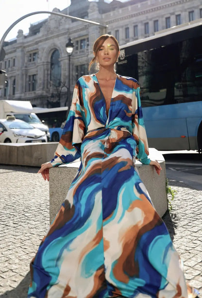 Modelo sentada com vestido longo Nomad fluido de manga morcego e saia estampada em tons de azul — Dress Eleven