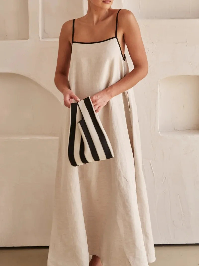 Detalhe frontal do vestido midi com alças finas e bolsa listrada, destacando o tecido estruturado e o caimento leve.


