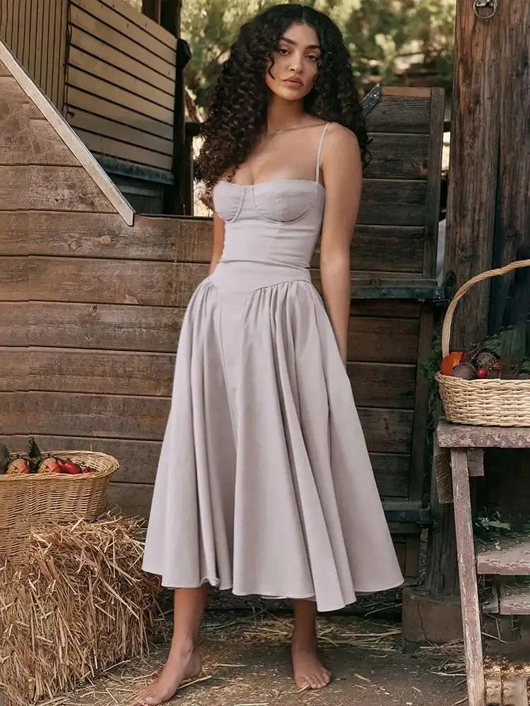 Vestido midi com cintura marcada e saia rodada, vista frontal completa em cenário campestre.