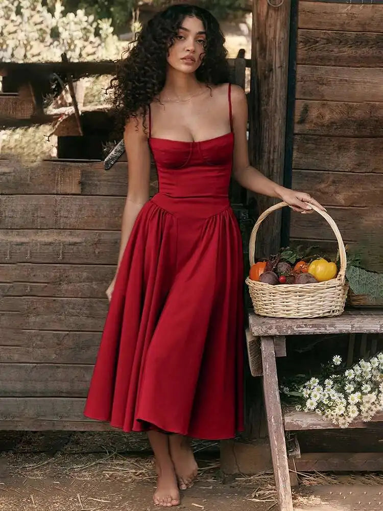 Vestido midi vermelho com cintura marcada e saia rodada, modelo segurando cesta de frutas em cenário rústico.