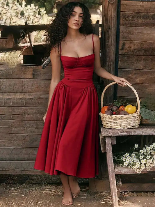 Vestido midi vermelho com cintura marcada e saia rodada, modelo segurando cesta de frutas em cenário rústico.