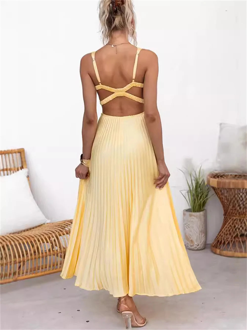 Vista traseira do vestido Solaré em cetim, com alças finas cruzadas e saia plissada fluida, fotografado em ambiente casual elegante.