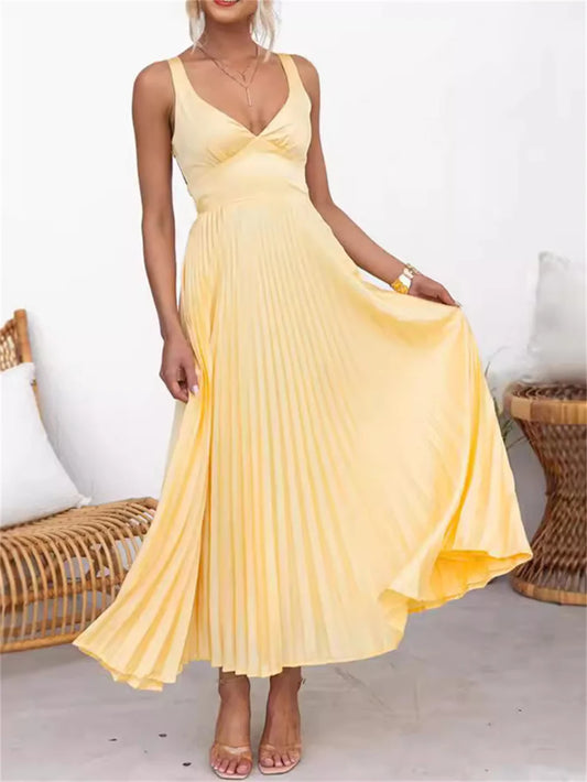 Vestido Solaré em cetim amarelo em movimento, destacando a fluidez da saia plissada e o charme das alças delicadas.