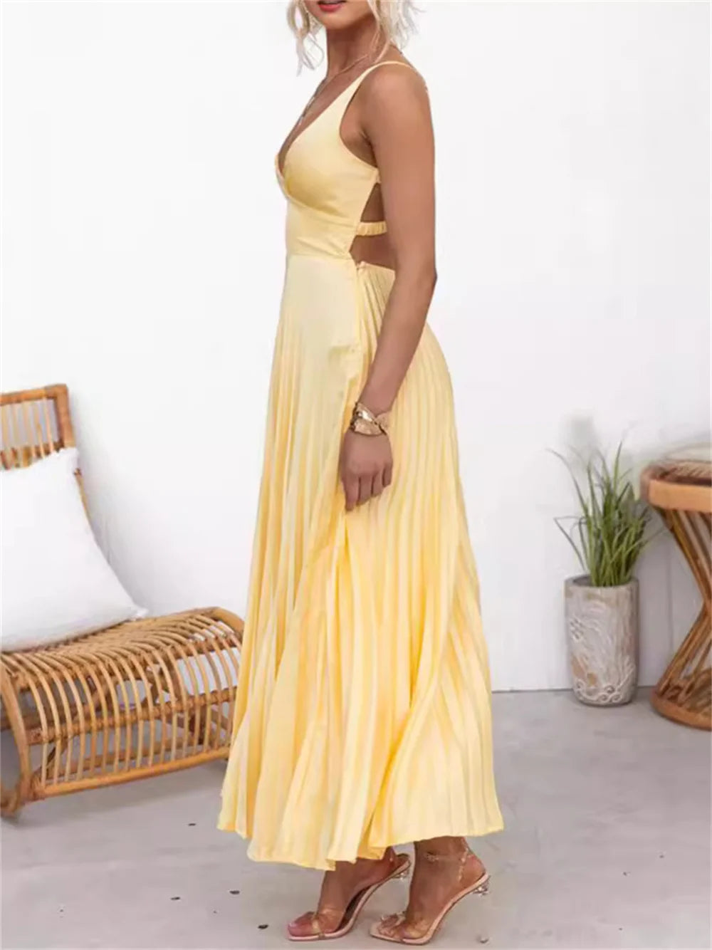 Vista lateral do vestido amarelo plissado em cetim, com alças finas e comprimento midi, ideal para eventos de verão com elegância.

