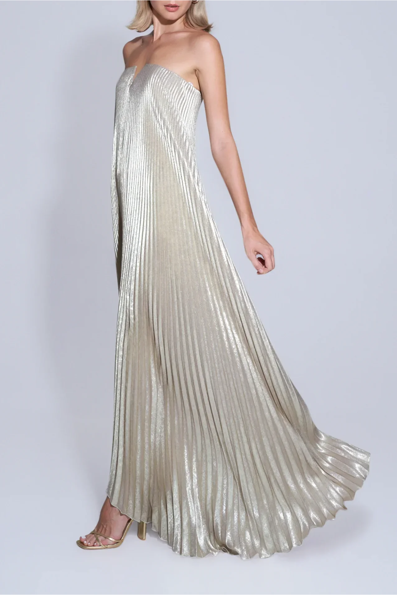 Vestido dourado plissado com caimento fluido em movimento, ideal para eventos sofisticados e festas de gala
