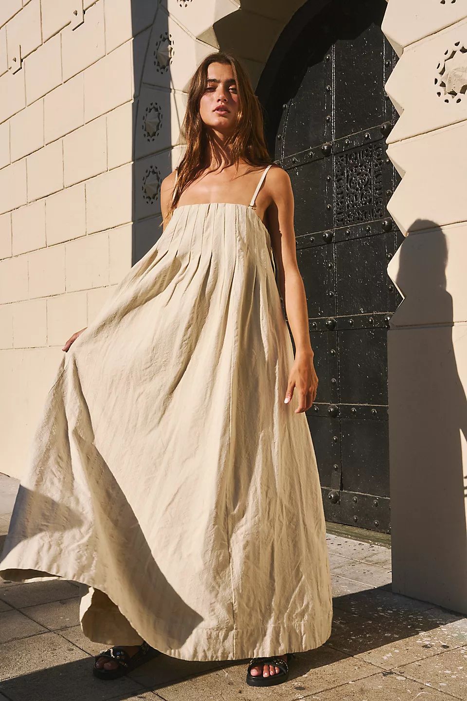  Modelo usando vestido de algodão bege com alças finas e caimento fluido, perfeito para dias quentes de verão.